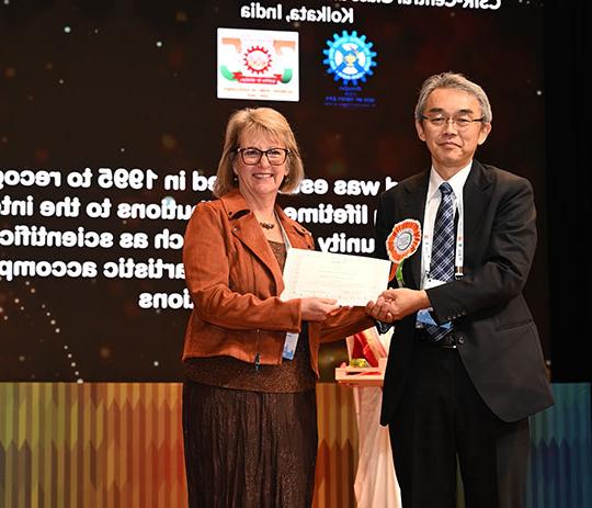 woman with glasses getting certificate from man in suit and tie