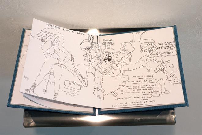 Inside look at a sketchbook with drawings of abstracted human figures in it and text.