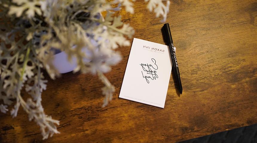 notepad and pen on desk that says enjoy your stay